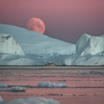 HUGE MOON PEEKING FROM BEHIND A LARGE ICEBERD IN ILULISSAT FJORD, GREENLAND