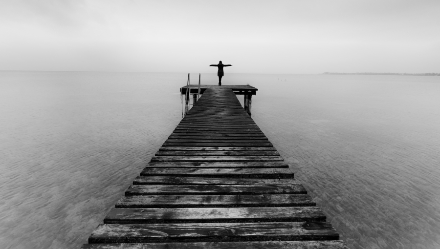 Woman standing at the end of a pier on a cloudy winter day